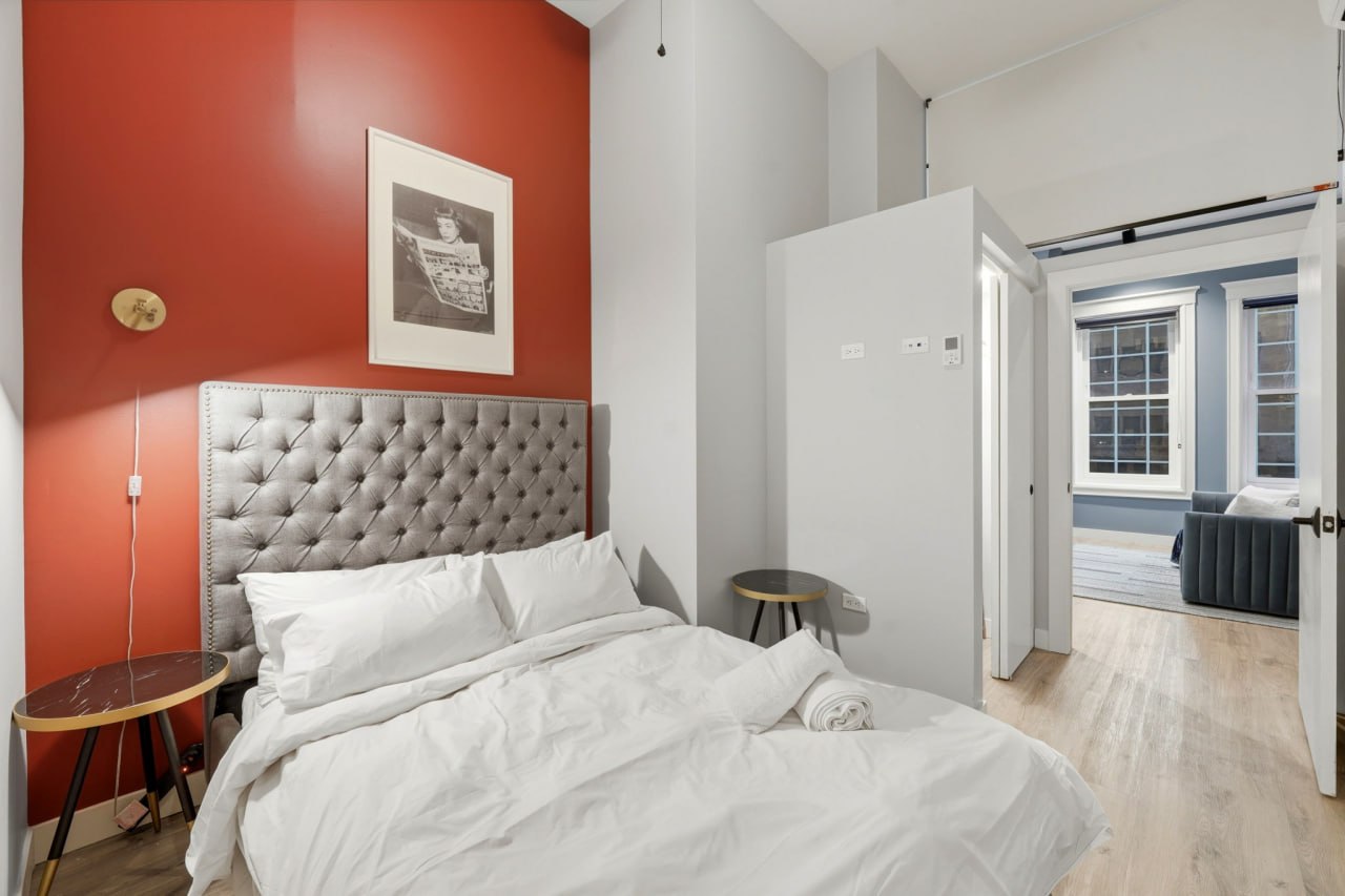 Red accent wall bedroom with tufted headboard and clean white bedding