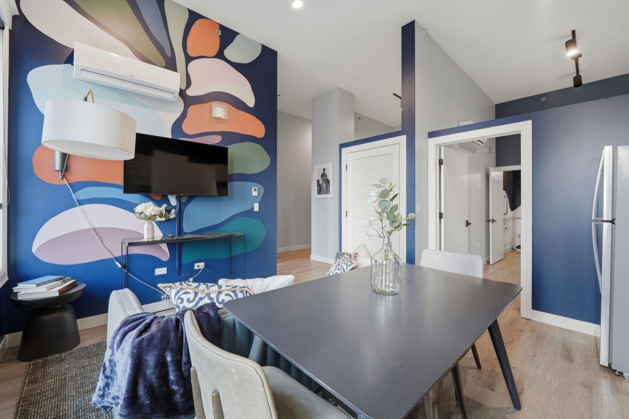 Bold colorful abstract mural with dining table and multiple bedrooms visible