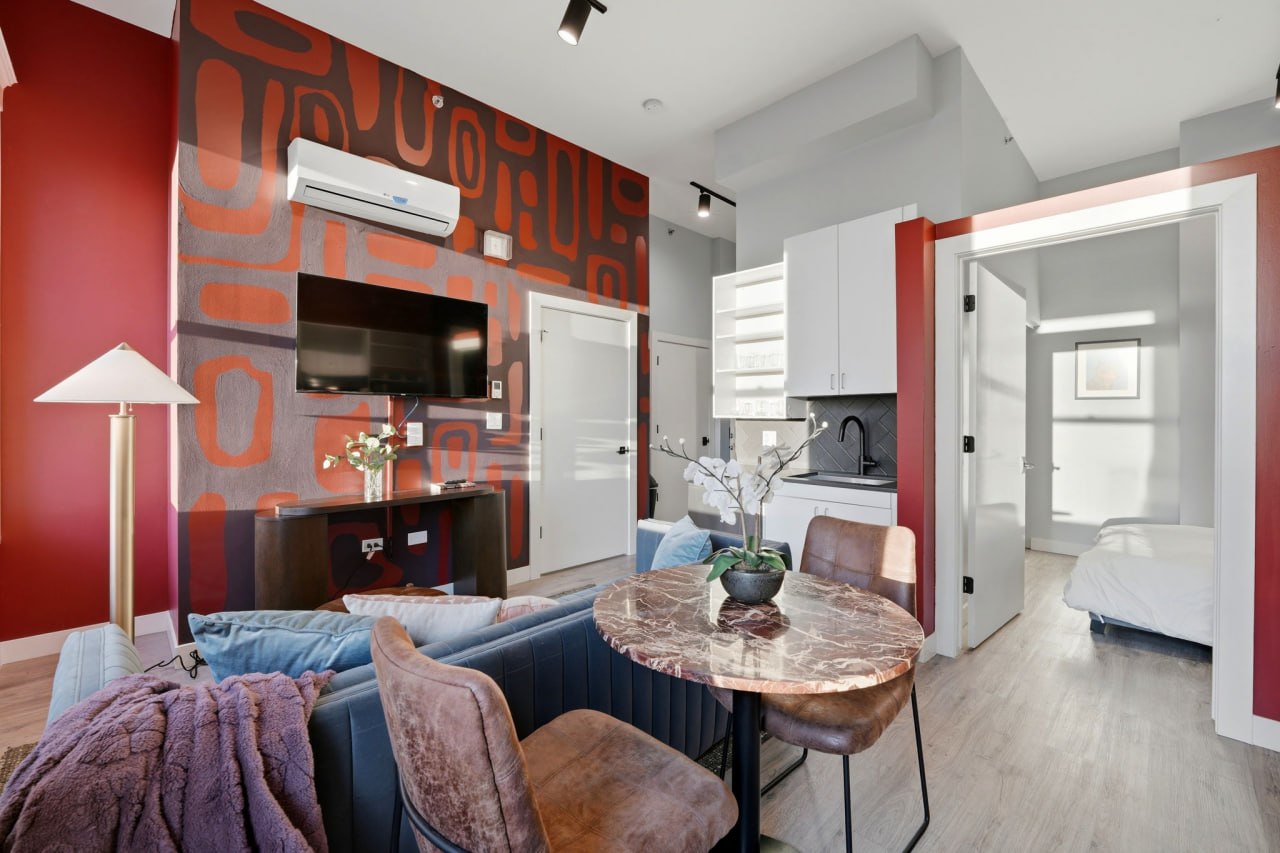 Red mural with marble dining table, kitchenette, and bedroom visible